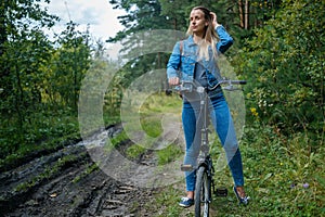 Woman in jeans riding on a bicycle at rural road