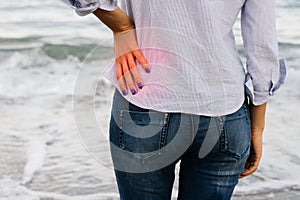 Woman in jeans and shirt standing on the shore and holding her l