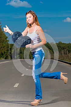 Woman in jeans and t-shirt travels hitchhiking