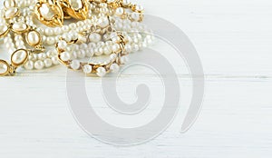 Woman Jewelry. Vintage jewelry background. Beautiful gold and pearl necklaces, bracelets and earrings on white wood. Flat lay,