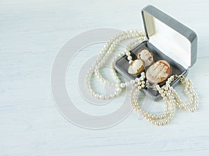 Woman Jewelry. Vintage jewelry background. Beautiful pearl necklace, bracelet and old cameos in a gift box on white wood. Flat