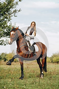 A woman jockey trains her horse to follow commands. The horse raises its leg at the command of the rider.