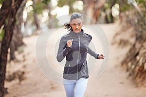 Woman, jog and fitness in forest for exercise, cardio training and wellness in outdoor activity. Athlete, serious and