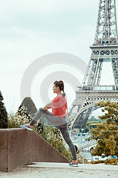 Woman jogger against clear view of Eiffel Tower stretching