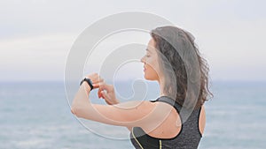 Woman jogger doing exercises and looking data on fitness smart watch