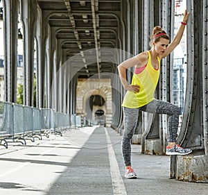 Woman jogger relaxing after workout on Pont de Bir-Hakeim bridge