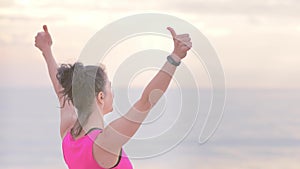 Woman jogger sport clothes on the seashore doing exercises, looking data on fitness watch