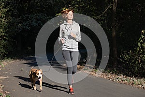 Woman jogging with dog in a park. Young female person with pet d