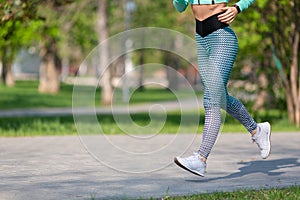 Woman jogging early in the morning in the park. Photo of legs of a running woman close-up. Concept of a healthy