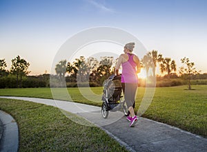 Woman jogging and exercising outdoors pushing her baby in a stroller