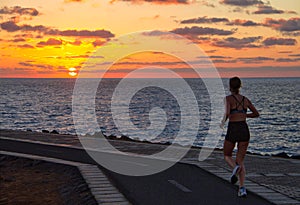 A woman jogging at sunrise on the coast, Caleta de Fuste, Fuerteventura, Canary Islands, Spain