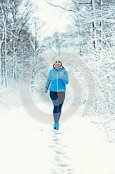 Woman jogging towards camera in cold and snowy forest