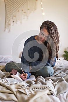 Woman journaling whilst sat on bed