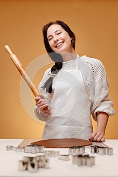 Woman joyfully holds a roller bake Christmas cookies.