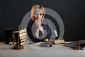 Woman judje isolated in office with books and justice scales and wooden gavel.
