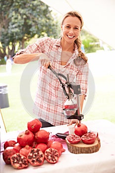 Woman Juicing Fresh Pomegranates At Farmers Market Stall photo