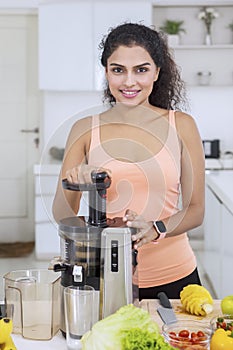 Woman juicing vegetables and fruits in kitchen