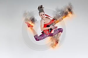 Woman in jump with a burning guitar