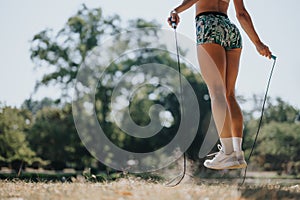 Woman jump rope in a park, displaying a healthy lifestyle and persistence in their fitness routine.