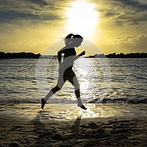 Woman jump / running on the beach at sunset.
