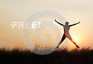 Woman jumping against sunset with word freedom