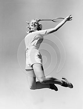 Una mujer saltando el aire tenis en su mano 