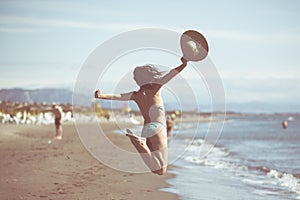 Woman jumping in the air on tropical beach,having fun and celebrating summer,beautiful playful woman jumping of happiness