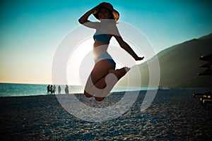 Woman jumping in the air on tropical beach,having fun and celebrating summer,beutiful playful woman in white dress jumping of hap photo