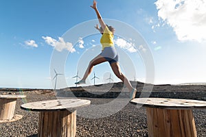 Woman jumping with arms outstretched with windmills in the background
