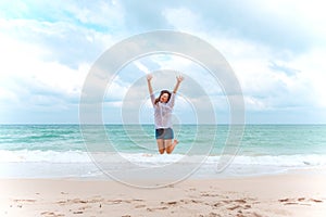 A woman jumping on the beach in front of the sea with feeling happy