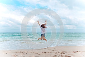 A woman jumping on the beach in front of the sea with feeling happy