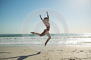 Woman jumping at beach on a sunny day