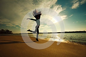 Woman jumping on the beach on sunny sky background