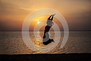 Woman jumping beautiful silhouette against the sea and dawn