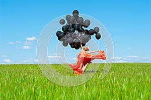 Woman jumping with black balloons in hands