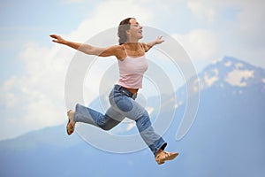 Woman is jumping with hands wide apart photo