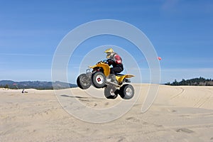 Woman jumping her ATV in the dunes