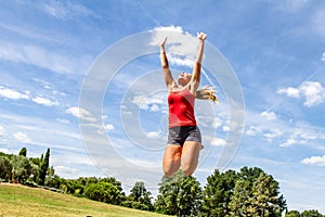 Woman jumping high to reach the sky in green park