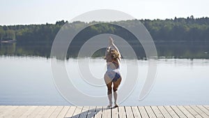 Woman jumping into the lake from wooden pier. Having fun on summer day. Young girl diving in to the water from the dock.