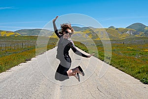 Woman jumping in the middle of the empty road in Carrizo Plain National Monument during the California superbloom
