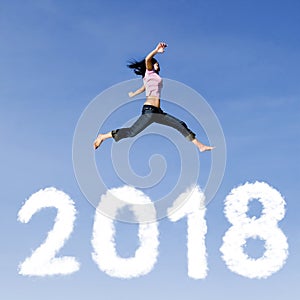 Woman jumping over clouds shaped of numbers 2018