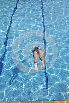 Woman jumping in the pool a summer day