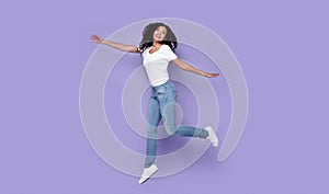 Woman Jumping Posing In Mid-Air Expressing Positive Emotions, Purple Background
