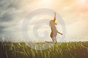 Woman jumping and raising up her hand and two finger over grass
