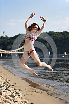 Woman jumping on the river beach