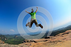 woman jumping on rocky mountain peak