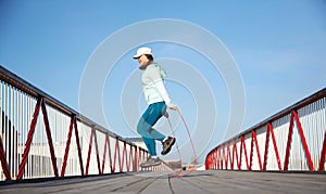 Woman jumping rope on a wooden bridge, cardio exercise outdoors