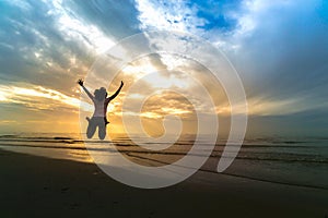 Woman jumping on sand at the sea in sunset. freedom life concept