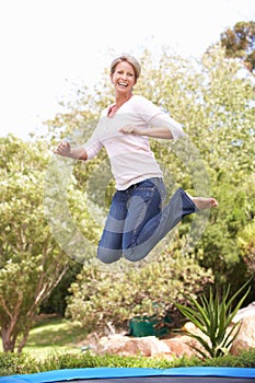 Woman Jumping On Trampoline In Garden photo