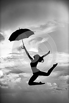 Woman jumping with umbrella. Ballet dancer isolated on sky background. Expressive artistic dance concept. Woman jump